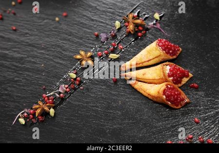 Pate di coniglio in corni croccanti decorato con spezie su un piatto di pietra nera Foto Stock