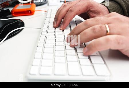 mani maschili tasti di digitazione su una tastiera bianca del computer in ufficio. Foto Stock