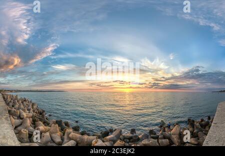 La struttura di mare è situata in una posizione densa sulla riva del tramonto. Mare mozzafiato. Tramonto dorato attraverso le nuvole blu. Il concep Foto Stock