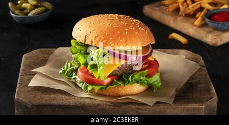Panorama Burger su uno sfondo scuro con sottaceti e patatine fritte Foto Stock