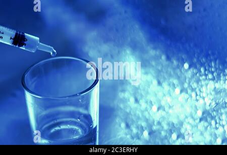 un ricercatore svuota il liquido da una fiala in un contenitore di vetro per trovare un vaccino contro il virus in un'analisi scientifica e ricerca Foto Stock