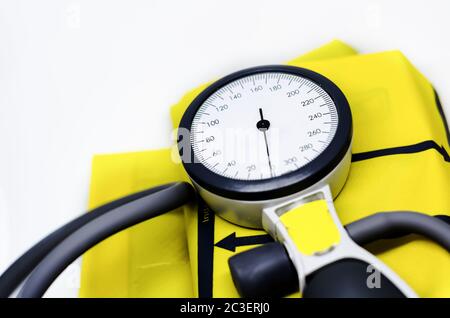 uno sfigmomanometro portatile poggiato su un bracciale giallo. Strumento per la misurazione della pressione sanguigna. Foto Stock