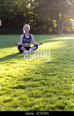 Donna (38) che pratica yoga su un prato nel parco, Kiel, Schleswig-Holstein, Germania Foto Stock