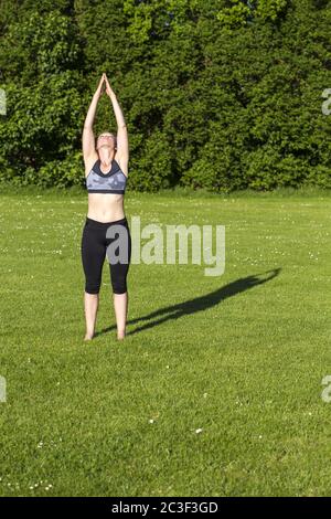 Donna (38) che pratica yoga su un prato nel parco, Kiel, Schleswig-Holstein, Germania Foto Stock