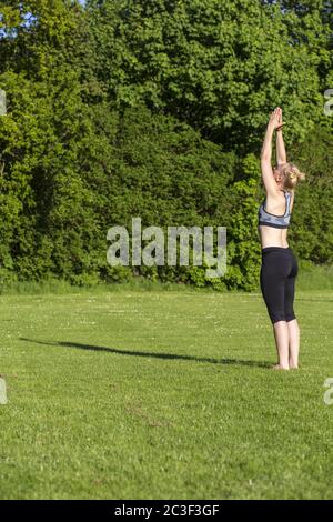 Donna (38) che pratica yoga su un prato nel parco, Kiel, Schleswig-Holstein, Germania Foto Stock