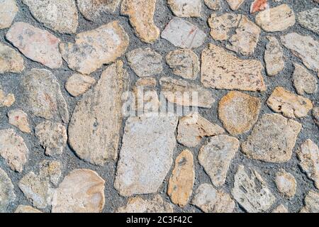 La strada pavimentata da pietre selvagge di varie forme. Pavimento in pietra selvaggia. Ripetizione di forme irregolari Foto Stock