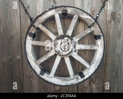 Vecchia ruota di legno su un muro di legno grigio. Foto di alta qualità Foto Stock
