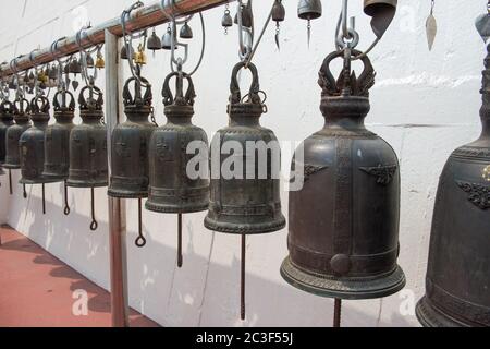 Fila di grandi campane tradizionali appese nel tempio buddista Foto Stock