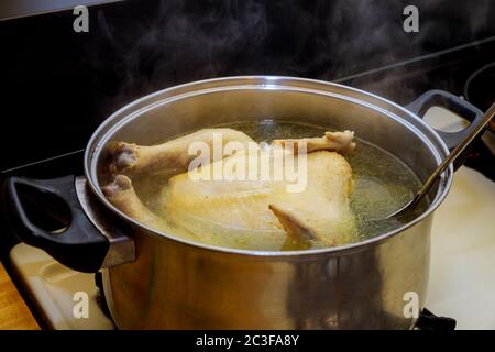 Zuppa di pollo o brodo con pollo intero nel recipiente. Foto Stock