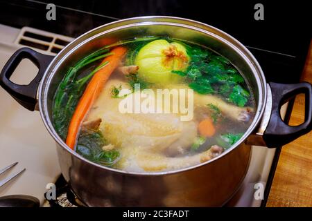 Brodo di pollo con carote, pollo intero, cipolla, sedano e prezzemolo in pentola. Foto Stock