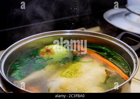 Versare il condimento nel brodo di pollo bollente con verdure in pentola di acciaio su piano cottura a gas. Foto Stock