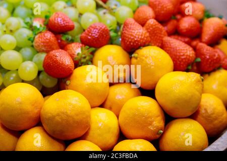 Frutta fresca. Mandarino e fragole con uva a fuoco dolce. Primo piano. Foto Stock