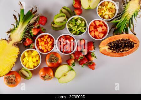 Frutti esotici e tropicali papaya, ananas, kiwi, mela, fragola e persimone . Tritare la frutta cubica per l'insalata. Foto Stock