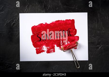 Rimani a casa, dipinto a mano su vernice rossa, messaggio di quarantena Covid-19 Foto Stock