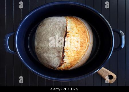 Pane di pasta acida in padella blu su fondo nero. Fotografia fatta in casa di pane alimentare. Illustrazione di alta qualità Foto Stock