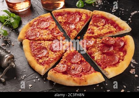Pizza ai peperoni su fondo nero Foto Stock