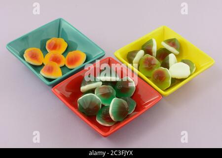 Caramelle dolci kiwi, limone e arancia con mela acida ripieno in piatti dolci su sfondo lavanda Foto Stock