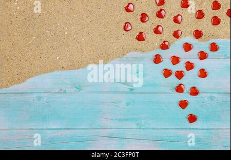 Tegole rosse sulla sabbia di mare su sfondo di legno blu. Concetto di giorno di San Valentino. Foto Stock