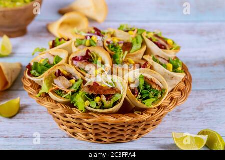 Tortillas al forno coni con lattuga e carne su sfondo di legno primo piano. Foto Stock