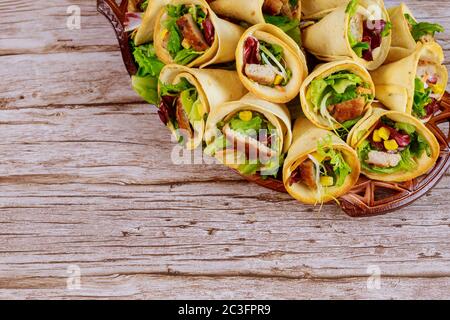 Coni di tortilla messicane ripieni di carne, mais e insalata su sfondo di legno. Foto Stock