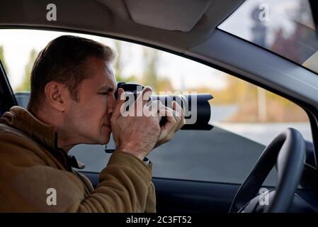 Giovane uomo con una fotocamera dslr in un'auto. Foto Stock