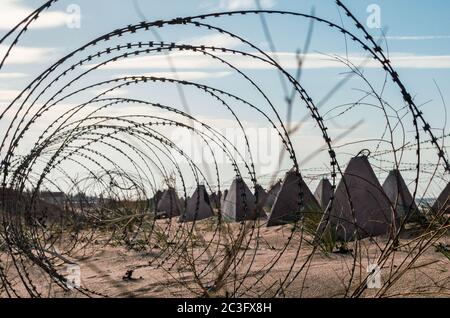 Filo spinato e recinto militare in cemento sulla spiaggia vicino al mare in Crimea Foto Stock