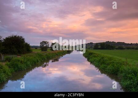 Glastonbury, Somerset, Regno Unito. 20 giugno 2020. Regno Unito Meteo. Le nuvole ad ovest illuminano rosa e si riflettono nel fiume Blue a Glastonbury nel Somerset durante l'alba del solstizio estivo. Immagine: Graham Hunt/Alamy Live News Foto Stock