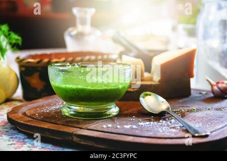 una ciotola di vetro con salsa di pesto fatta in casa su un tavolo di legno con un mortaio sullo sfondo in un rustico Foto Stock