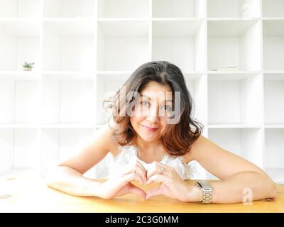 Pretty Woman con faccina felice superficie a forma di cuore dalle sue mani. Foto Stock