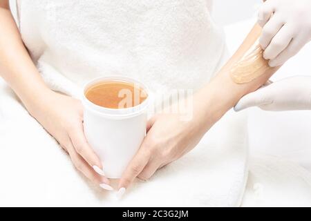 Epilazione indesiderata con cera per capelli. Giovane Donna. Procedura di trattamento del salone di cosmetologia. Ceretta domestica Foto Stock