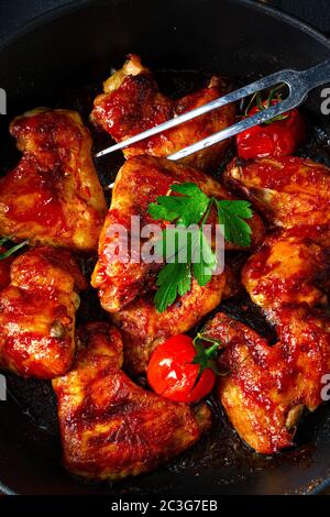 Ali di pollo speziate al miele con spicchi di patate Foto Stock