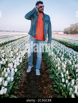 Giovane ragazzo in campo di tulipano fiore durante il tramonto, giovani uomini in campo di tulipano nei Paesi Bassi Noordoostpolder Foto Stock