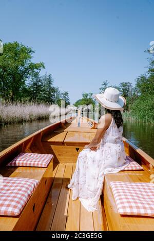 Giethoorn olandese donna visitare il villaggio con una barca, vista del famoso villaggio con canali e rustiche case tetto in paglia Foto Stock