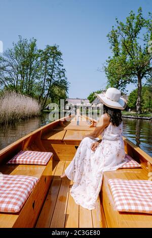 Giethoorn olandese donna visitare il villaggio con una barca, vista del famoso villaggio con canali e rustiche case tetto in paglia Foto Stock