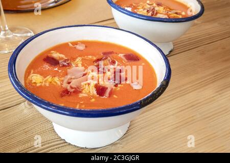 Salmorejo, zuppa spagnola di pomodoro freddo in una ciotola rustica su un tavolo di legno Foto Stock