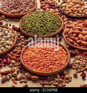 Assortimento di legumi su sfondo marrone. Lenticchie, soia, ceci, fagioli rossi, una ventietà di impulsi, colpo quadrato Foto Stock