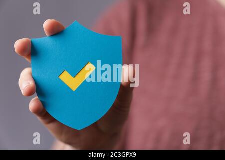 Uomo che tiene uno scudo di protezione con un segno di spunta Foto Stock