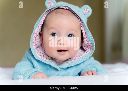 una bella ragazza blu degli occhi neonato si trova sul pancino e sorride Foto Stock