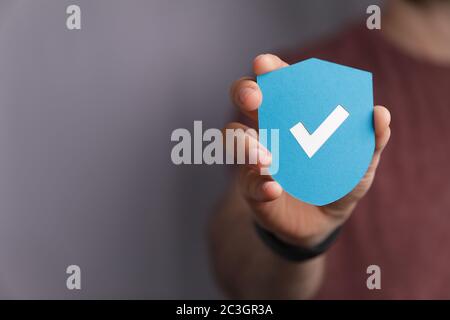 Uomo che tiene uno scudo di protezione con un segno di spunta Foto Stock