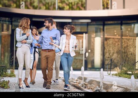 colleghi caucasici che camminano e parlano di fronte al business building Foto Stock