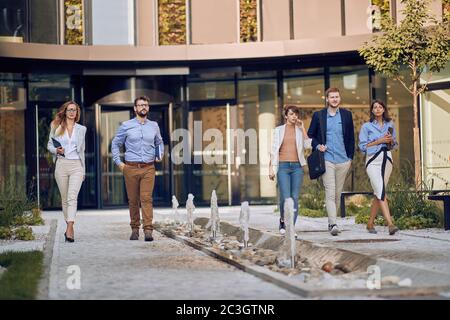 uomini d'affari caucasici che camminano e parlano di fronte all'edificio degli affari Foto Stock