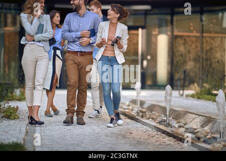 immagine tagliata di colleghi caucasici che camminano, parlano e ridono di fronte al business building Foto Stock