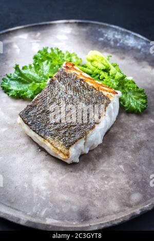 Filetto di merluzzo europeo fritto gourmet skrei con rapini broccoli come primo piano su una piastra di design moderno Foto Stock