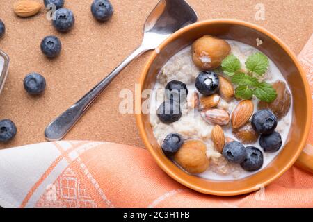 ciotola di porridge di farinata d'avena con mirtilli, frutta, mandorle e latte di cocco. vega sana e gustosa Foto Stock