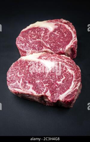 La bistecca di manzo secca di wagyu invecchiata grezza è considerata come una chiocciatura su sfondo nero con spazio per la copia Foto Stock