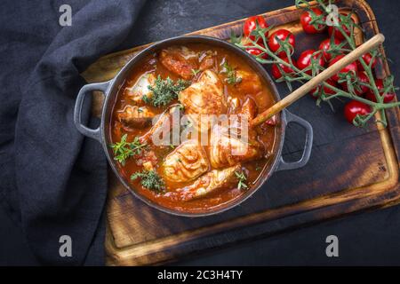 Tradizionale stufato di pesce brasiliano moqueca baiana con filetto di pesce in salsa di pomodoro come vista dall'alto in una moderna tostatura in ghisa Foto Stock