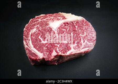 La bistecca di manzo secca di wagyu invecchiata grezza è considerata come una chiocciatura su sfondo nero con spazio per la copia Foto Stock