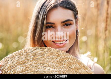 Primo piano ritratto di una donna sorridente che tiene un cappello di paglia Foto Stock