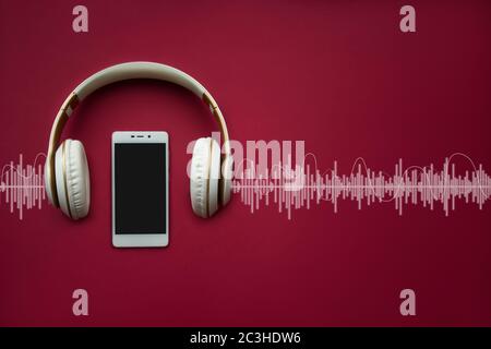 Moderno cellulare Bianco modello e cuffie su sfondo rosso gradiente con traccia Audio. Concetto musicale Foto Stock