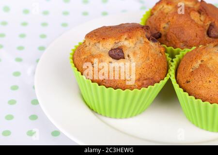 Muffin al cioccolato alla banana su piatto bianco con tovaglie macchiate di verde e bianco. Foto Stock